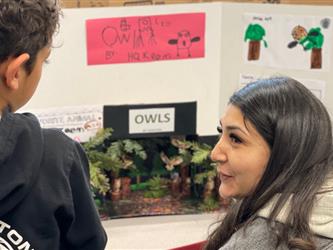 Young student explains project to a parent volunteer